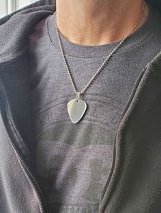 a man wearing a necklace with a heart shaped pendant hanging from it's side