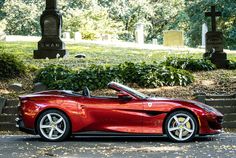 a red sports car parked in front of a grave