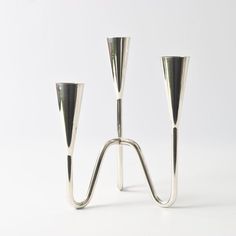 two silver candlesticks on a white background with one candle holder in the middle