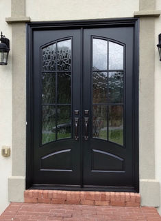 a black double door with two sidelights and brick walkway leading up to the entrance