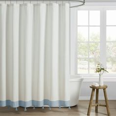 a white and blue shower curtain next to a bathtub in a room with wooden floors