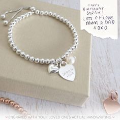 "Our beautiful range of engraved handwriting jewellery makes a beautiful dedication to a loved one, all it takes is a photo of their handwriting for our engraving team to work from. This beautiful silver bracelet combines a silver heart charm, perfect for engraving a name or a short message from a handwriting sample, alongside a beautiful pearl and a dainty silver puffed heart charm. The sterling silver heart charm measures 12mm across the front of the heart and sits centrally on a sterling silv Engraved Sterling Silver Name Bracelet For Mother's Day, Engraved Sterling Silver Bracelets For Mother's Day, Mother's Day Sterling Silver Engraved Bracelets, Mother's Day Engraved Sterling Silver Bracelets, Personalized White Gold Charm Bracelet For Mother's Day, Engraved Name Bracelet For Mother's Day Anniversary, Engraved Name Bracelet For Anniversary Mother's Day, Sterling Silver Name Bracelet With Heart Charm For Gift, Engraved Name Bracelet For Anniversary And Mother's Day