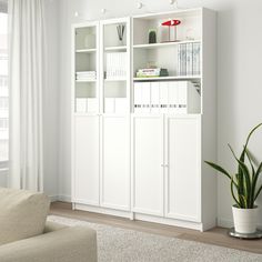 a living room filled with furniture and a white bookcase next to a window on top of a carpeted floor