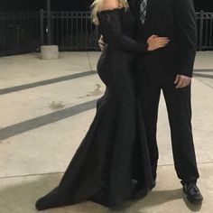 a man and woman dressed in formal wear posing for the camera at an outdoor event