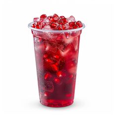 a plastic cup filled with lots of red liquid next to a pile of pomegranates