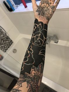 a person's arm with tattoos on it in front of a bathtub and sink