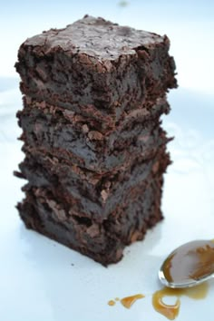 a stack of brownies sitting on top of a white plate next to a spoon