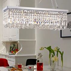 a crystal chandelier hanging from the ceiling in a dining room with red chairs