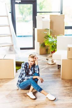 a woman sitting on the floor in front of boxes