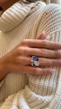 a woman's hand with a ring on top of her arm, wearing a white sweater