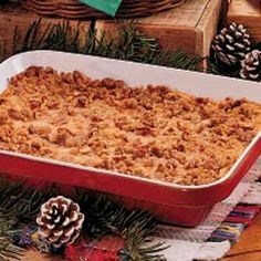 a red casserole dish filled with food next to pine cones