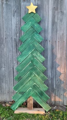 a green christmas tree made out of wooden planks with a gold star on top