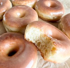 several glazed donuts sitting on top of wax paper