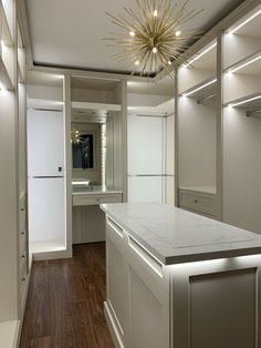 a white kitchen with an island counter and lights on the ceiling, along with wooden flooring