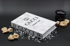 a gucci box and some flowers on a black surface with white flecks