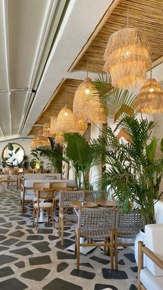 a restaurant with tables, chairs and plants in the middle of the room that is lined up against the wall