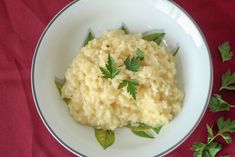 mashed potatoes with parsley in a white bowl on a red tablecloth next to green leaves