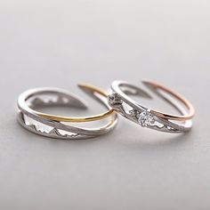 two gold and silver wedding rings with diamond accents on each band, sitting side by side