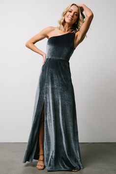 a woman in a black and grey dress posing for the camera with her hand on her head