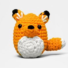 a crocheted stuffed animal holding a white ball in it's paws, on a white background