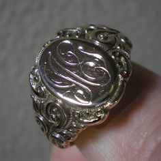 Such a beautiful ring for they guys but could be sized down for the ladies, within reason. This ring has fabulous scroll detailing on the shoulders. The oval face area is approx. 5/8 inches long and under 1/2 inch wide. Marks are the back 10 k and tested as such. Ring is heavy at 8.8 grams and approx. a size 13. This ring has been size up in the past. You can feel a slight ripple in the band in back as well as it being a bit thinner. Not an issue but an observation. The initials on the face look Heirloom Engraved Ring Jewelry, Classic 14k Gold Engraved Ring With Intricate Design, Luxury Oval Signet Ring With Intricate Design, Luxury Signet Ring With Intricate Design For Anniversary, Classic Intricate 14k Gold Jewelry, Silver Heirloom Initial Ring For Wedding, Formal Silver Initial Ring Stamped 14k, Vintage White Gold Jewelry With Engraving Option, Engraved Victorian 14k Gold Jewelry