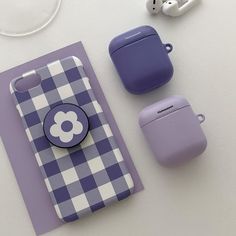 an assortment of cell phones and earbuds on a white table with a purple checkered case