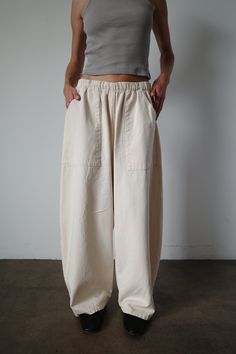 Our take on the everyday pant. Made with an elegantly curved leg, comfortable elastic waist band and large front patch pockets. This pant seamlessly blends comfort and style. An instant classic. Model is 5'6" and wearing the size small. Relaxed Fit Tapered Pants With Elastic Waistband, Relaxed Fit Bottoms For Elevated Casual Wear, Relaxed Fit Pants With Pull-on Style, Solid Color Pants With Pull-on Style And Relaxed Fit, Relaxed Fit Pull-on Solid Pants, Elevated Casual Relaxed Fit Pull-on Bottoms, Elevated Casual Bottoms With Relaxed Fit, Solid Color Wide Leg Pants With Relaxed Fit, Elevated Casual Ankle-length Pants With Pockets