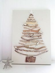 a christmas tree made out of driftwood is displayed on a white wall next to a starfish