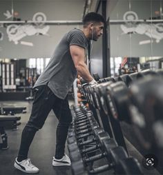 a man working out in the gym with dumbbells and weight machines behind him