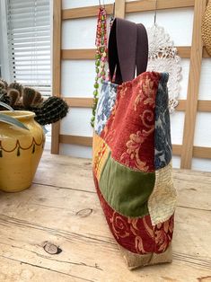 a multicolored bag sitting on top of a wooden table next to a potted plant