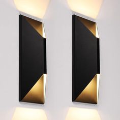 two black and gold wall lights mounted to the side of a white wall next to each other