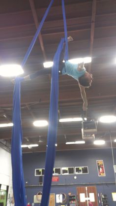 a man on a high jump in the middle of an indoor gym with blue ribbon