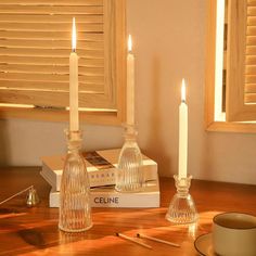 two candles are sitting on a table next to some books