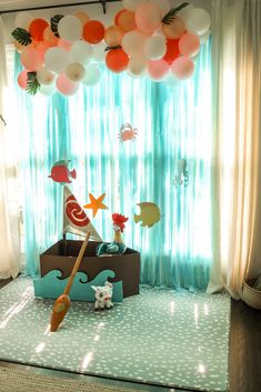 a room filled with balloons and decorations on the floor next to a curtained window