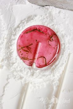 a pink object with writing on it sitting in the middle of white powdered paper