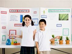 two children standing next to each other in front of a science fair display with posters on it