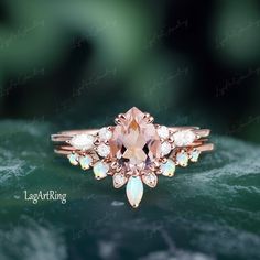 a ring with an oval shaped morganite surrounded by small white opal and diamond accents