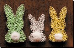 three bunny shaped string art ornaments on a table with yarn balls in the shape of rabbits