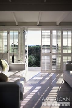 an open living room with white shutters and couches