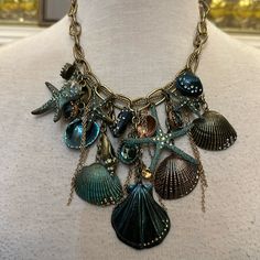 a necklace with shells and seashells hanging from it's centerpiece on a mannequin