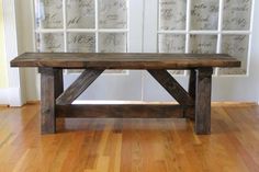 a wooden bench sitting on top of a hard wood floor next to a wall with writing on it