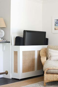 a living room with wicker furniture and a flat screen tv on top of a cabinet