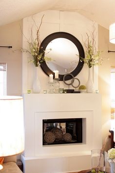 a living room filled with furniture and a fire place under a round mirror on the wall