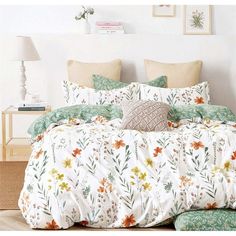 a bed covered in white and green floral comforters