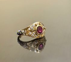 DeKara Designs Collection Metal- 18K Yellow Gold, .750. Stones- 1 Oval Ruby 0.50, 28 Round Diamonds G Color VS2 Clarity 0.22 Carats. Art Deco 18K Yellow Gold Ruby Diamond Engagement Ring. This ring features a beautiful reddish pink ruby that is half carat total weight, surrounded by 28 round diamonds. The center ruby is bezel set, 20 pave set diamonds, and 8 bezel set diamonds. The ring is entirely handmade, and could be hand engraved for an additional $200.00. The ring is a size 6 1/2, and coul Yellow Gold 22k Ruby Wedding Ring, 22k Yellow Gold Ruby Wedding Ring, 22k Yellow Gold Ruby Ring For Wedding, Fine Jewelry Yellow Gold Ruby Ring With Intricate Design, Yellow Gold Hallmarked Ruby Ring For Wedding, Hallmarked Yellow Gold Ruby Ring For Wedding, Luxury Gold Ruby Ring With Intricate Design, Yellow Gold Ruby Ring With Intricate Design, Heirloom Gold Ruby Ring With Rose Cut Diamonds