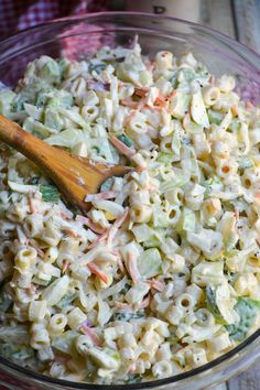 a bowl filled with macaroni salad and a wooden spoon