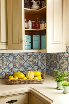 some bananas and lemons in a wicker basket on the kitchen counter next to cabinets