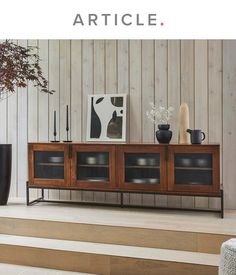 a wooden entertainment center sitting on top of a set of steps next to a vase