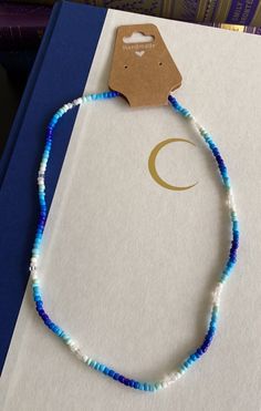 a blue and white beaded necklace sitting on top of a book