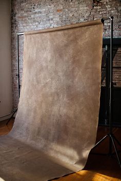 a photo studio with a brown backdrop in front of a brick wall and wooden floor